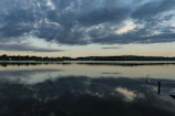 A dramatic landscape with stormy clouds over a quiet lake reflecting the sky.