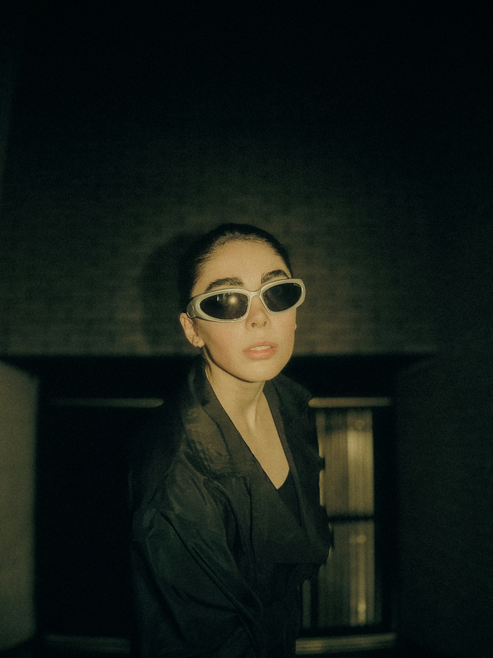 a woman wearing a pair of sunglasses in a dark room