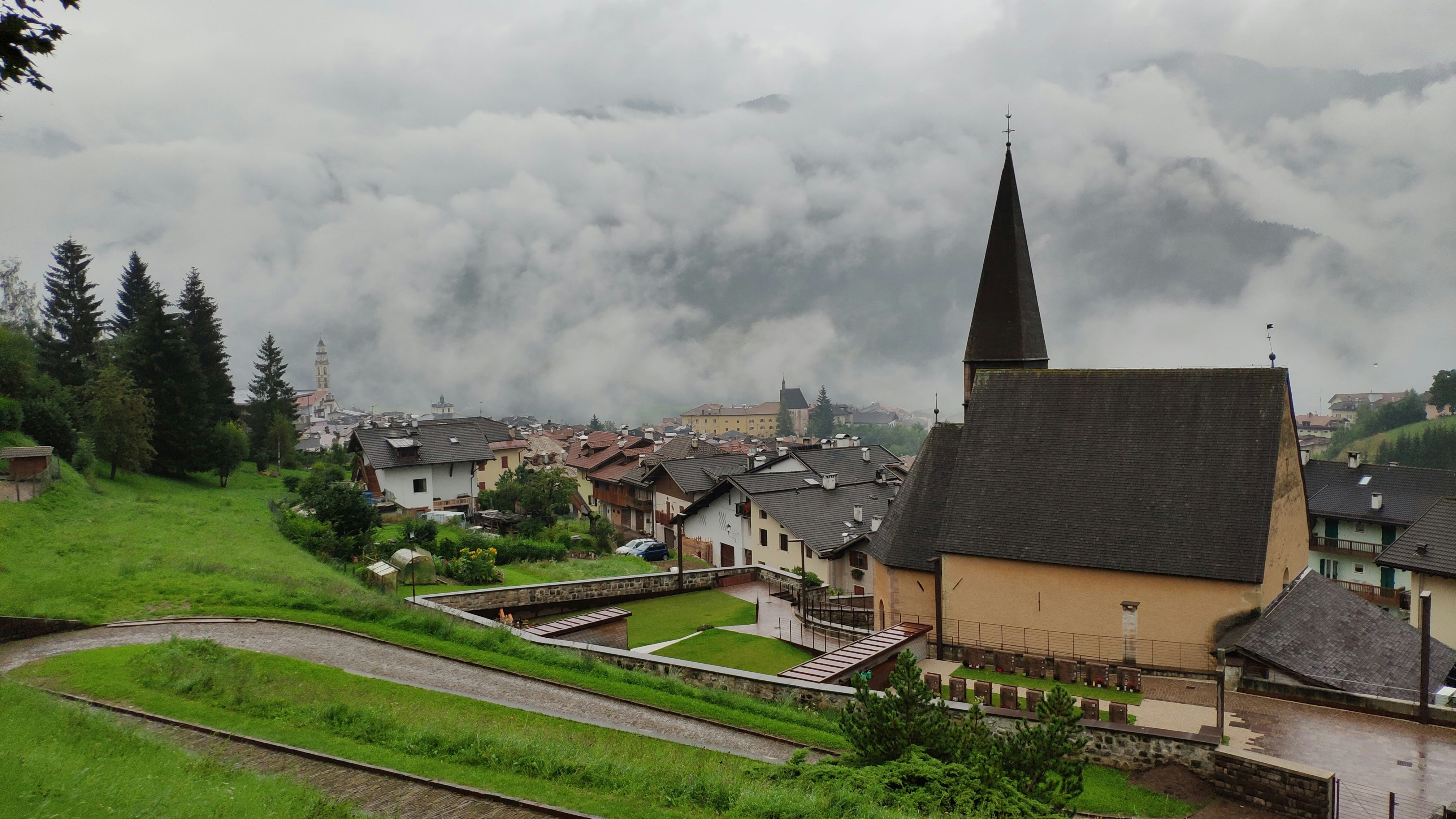 A small village with a steeple on a cloudy day photo – Free Via san