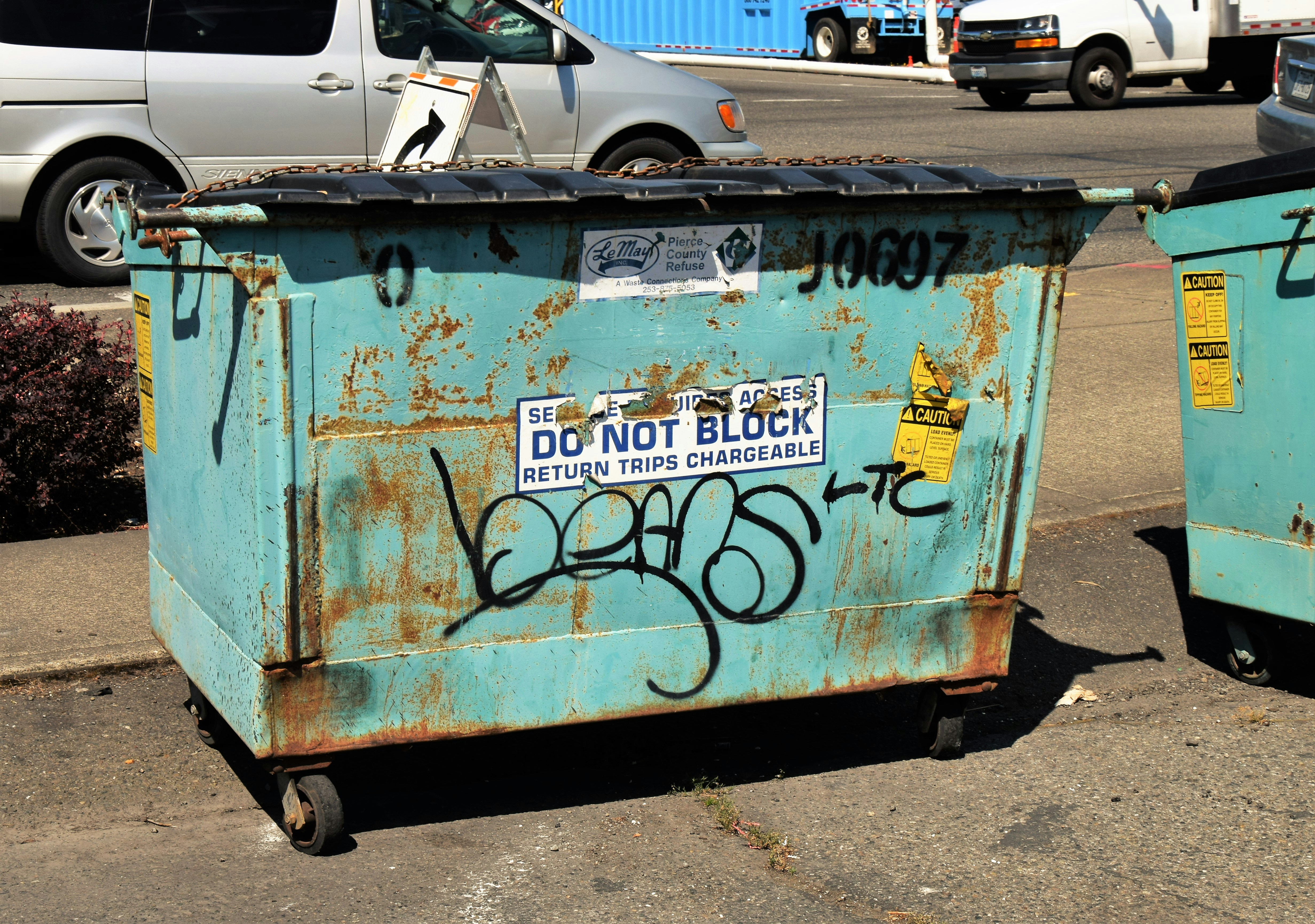 a blue trash can sitting on the side of a road