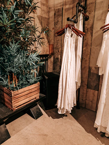 Industrial greenhouse studio setting with iron gears and cream-toned garments hanging gently.