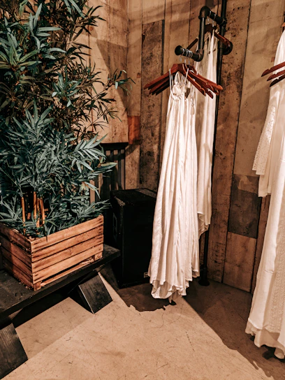 A cozy, sunlit studio with racks of colorful sustainable clothing and plants around.