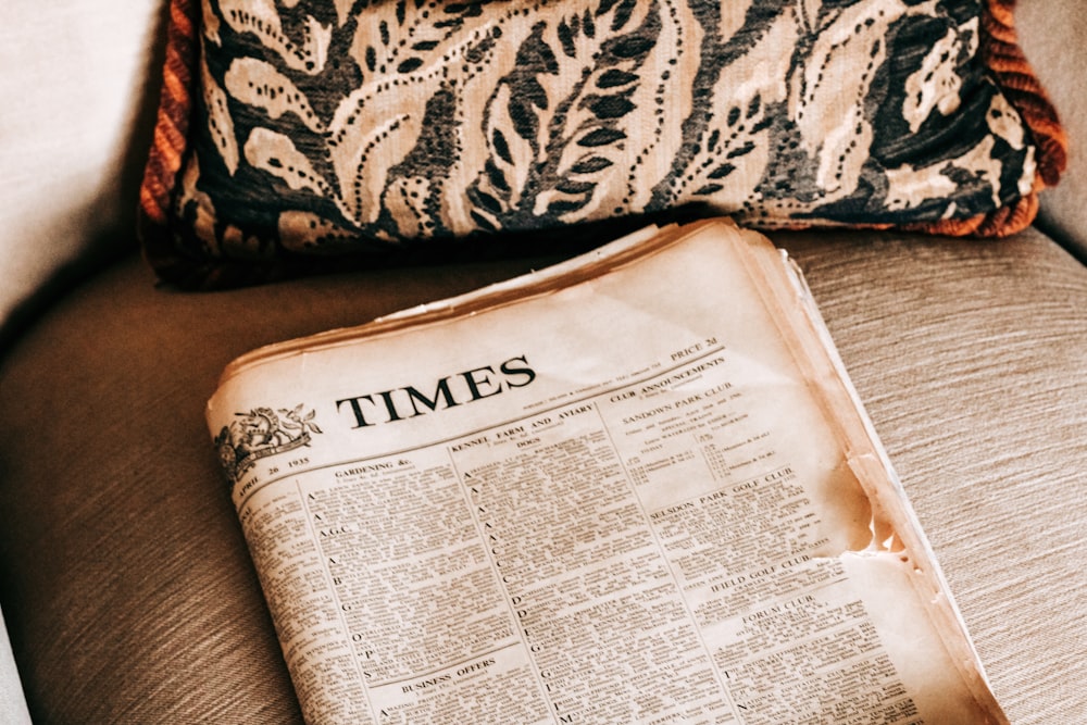 an old newspaper sitting on a couch next to a pillow