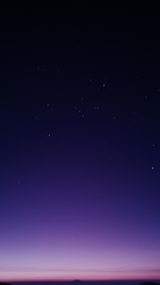 Silver and gold shimmering stars scattered across a deep violet twilight