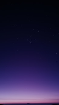 A serene twilight sky blending deep navy and purple hues with shimmering gold stars, evoking a mystical atmosphere.
