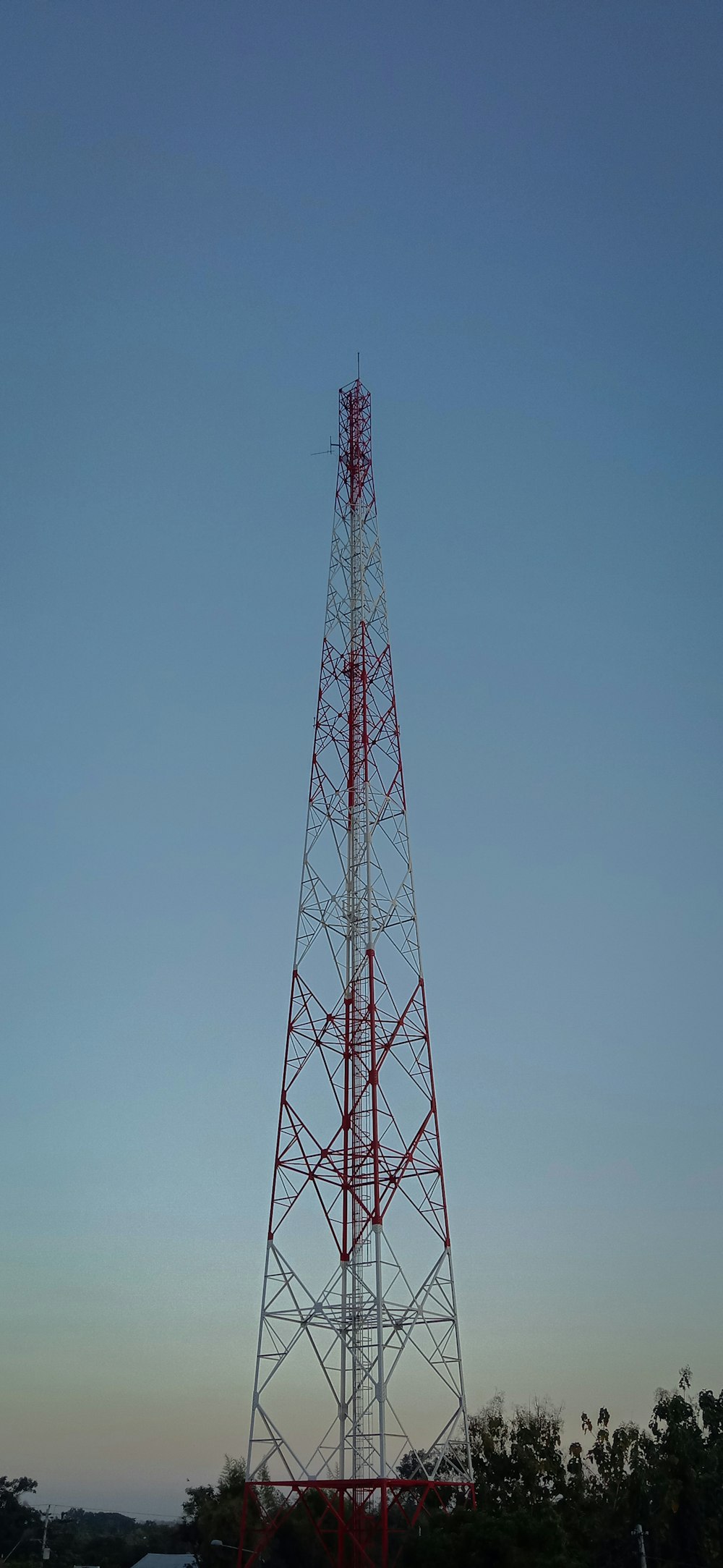 a red and white tower sitting in the middle of a field