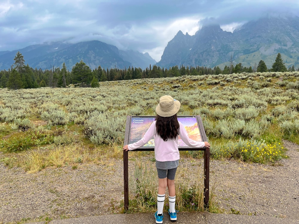 a little girl that is standing in front of a sign