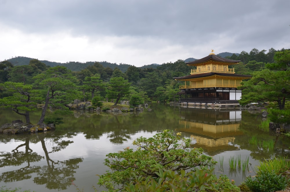 a yellow building sitting on top of a lake next to a forest