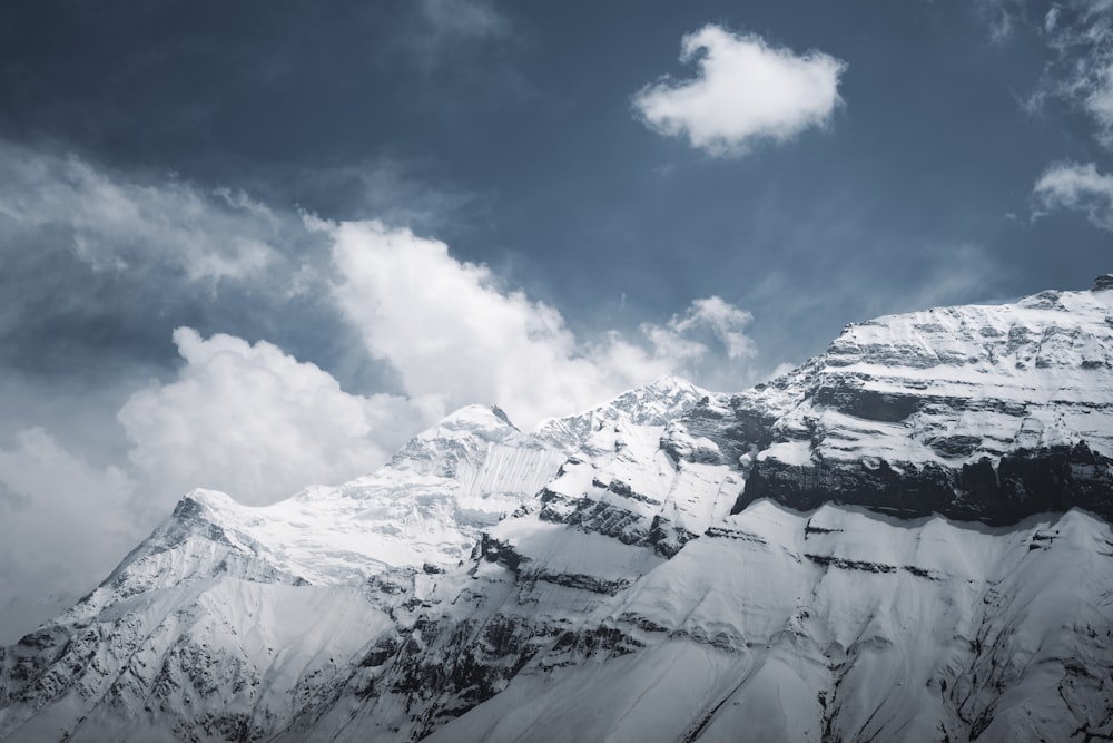 a mountain covered in snow under a cloudy sky