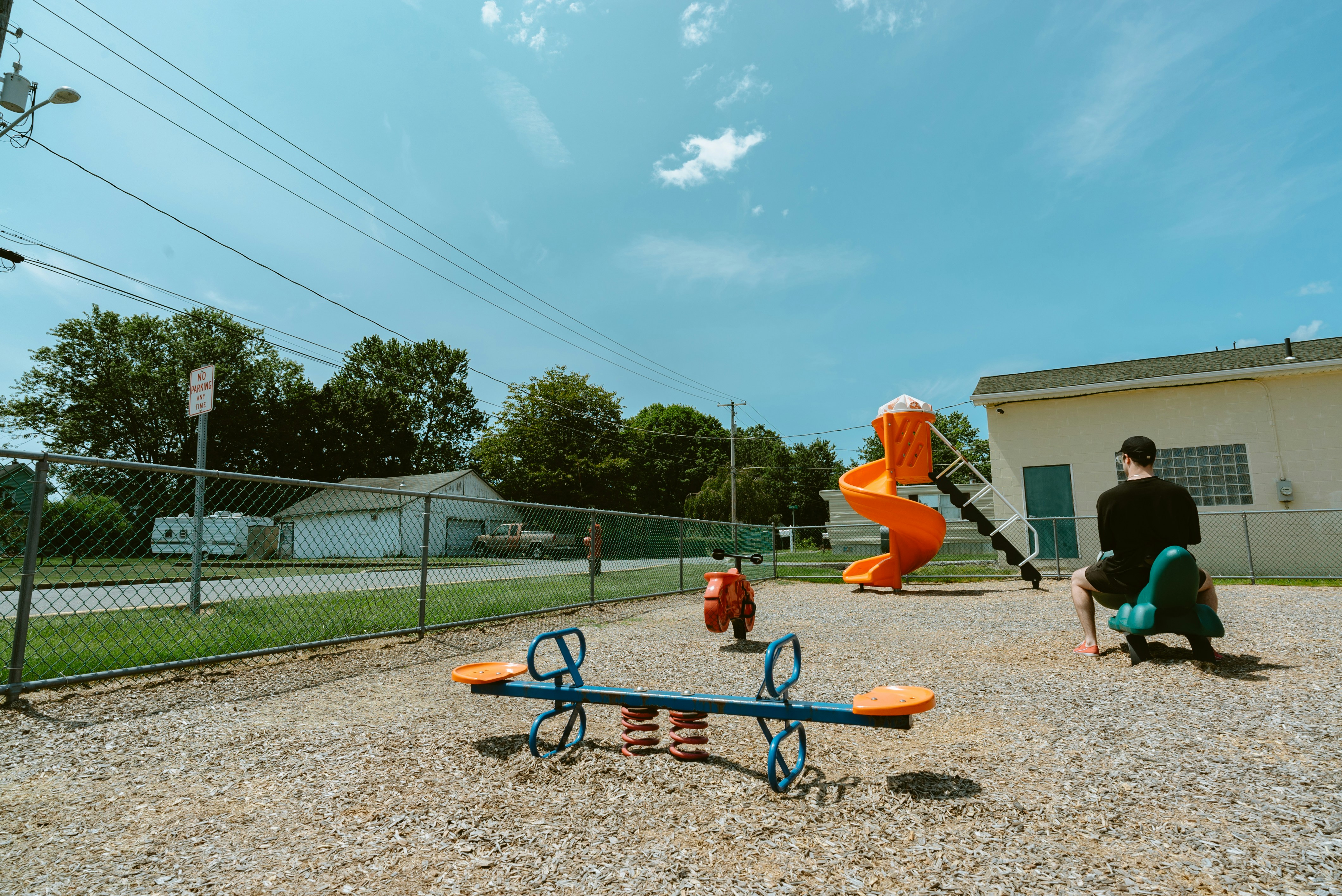 Ein Mann, der auf einer Bank neben einem Spielplatz sitzt