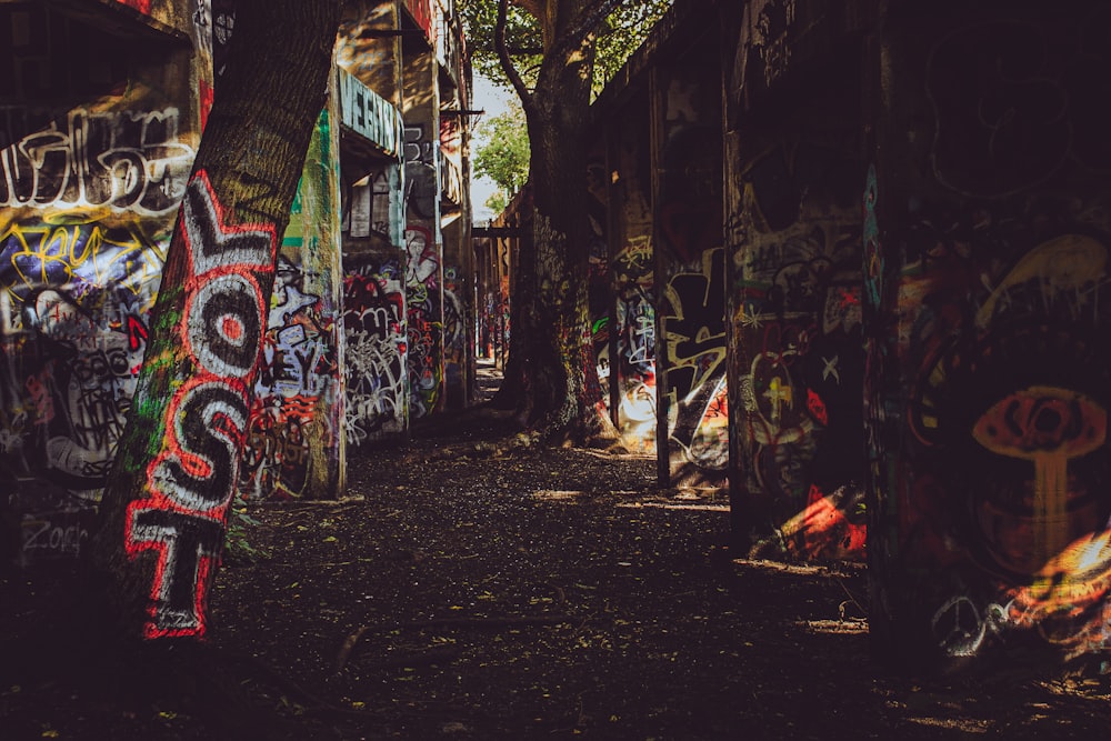 a narrow alley with graffiti all over the walls