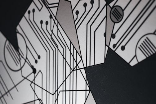 An abstract design featuring geometric shapes and circuit-like patterns with black lines on a light gray background. The intersecting lines and circles resemble a circuit board, creating a modern and technological aesthetic.