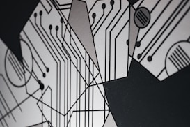 An abstract design featuring geometric shapes and circuit-like patterns with black lines on a light gray background. The intersecting lines and circles resemble a circuit board, creating a modern and technological aesthetic.