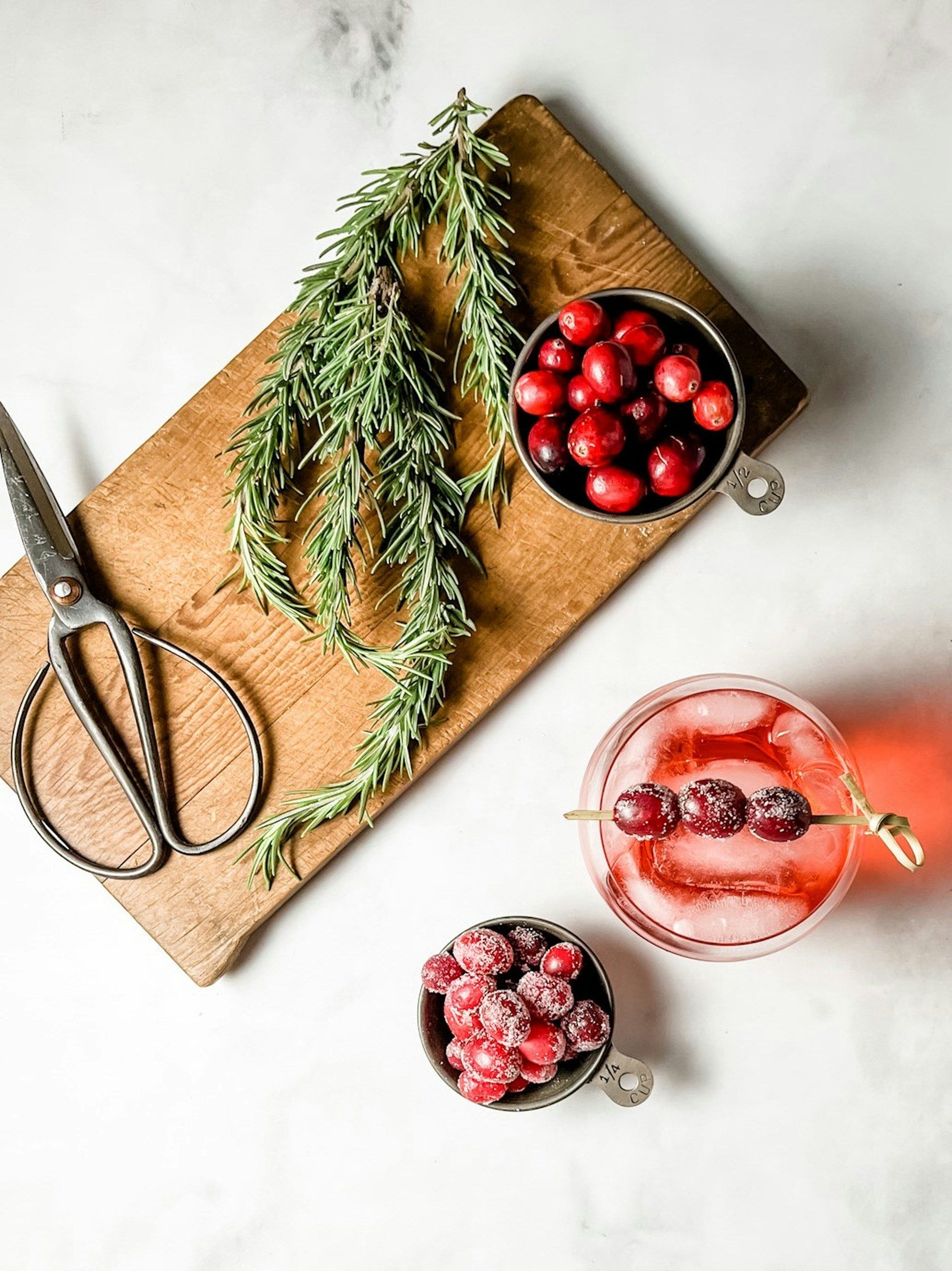 a cutting board topped with a bowl of cranberries next to a bowl of