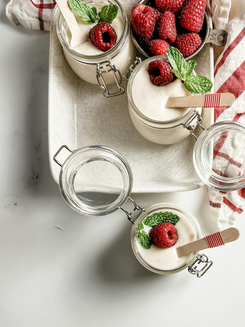 a white tray topped with desserts covered in whipped cream and raspberries