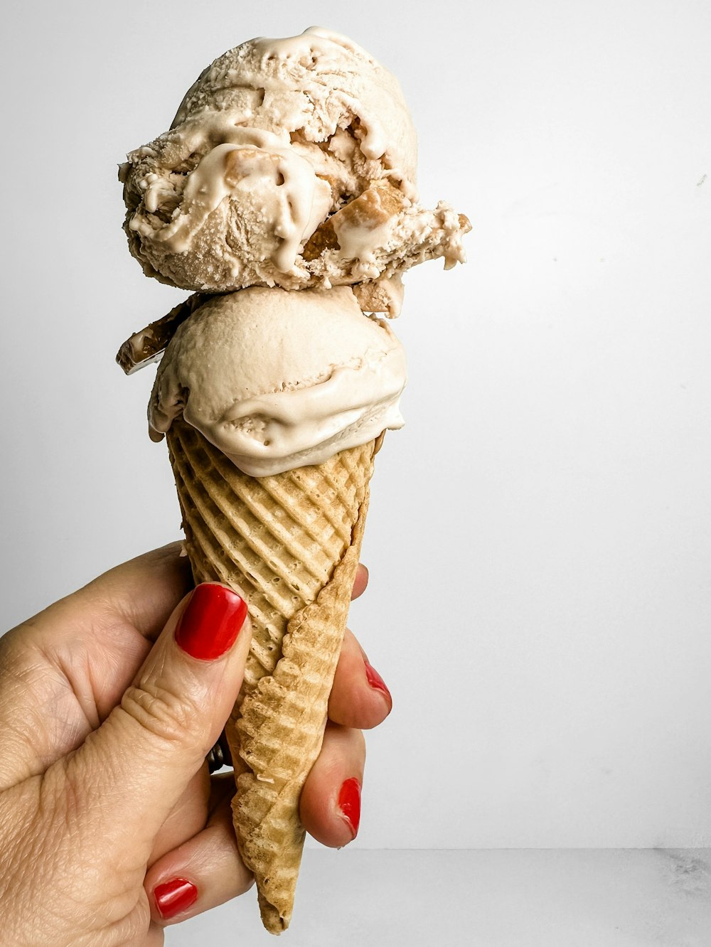 a hand holding an ice cream cone with two scoops