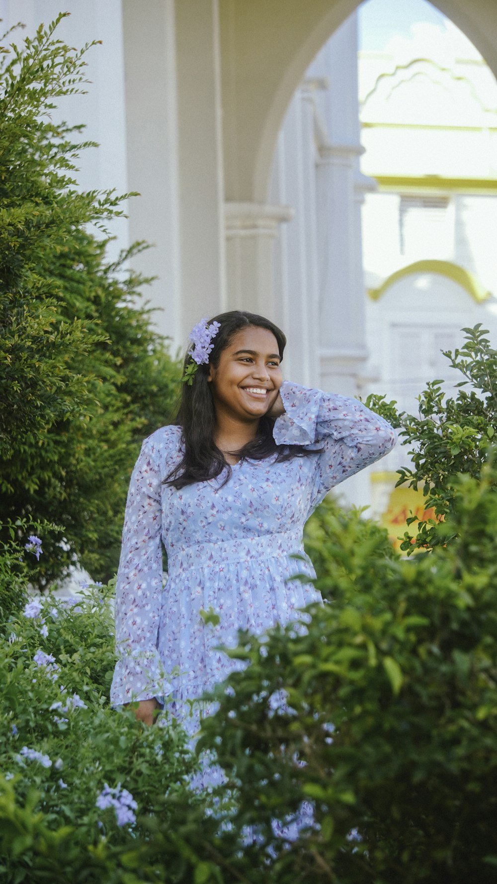 a woman in a blue dress standing in a garden