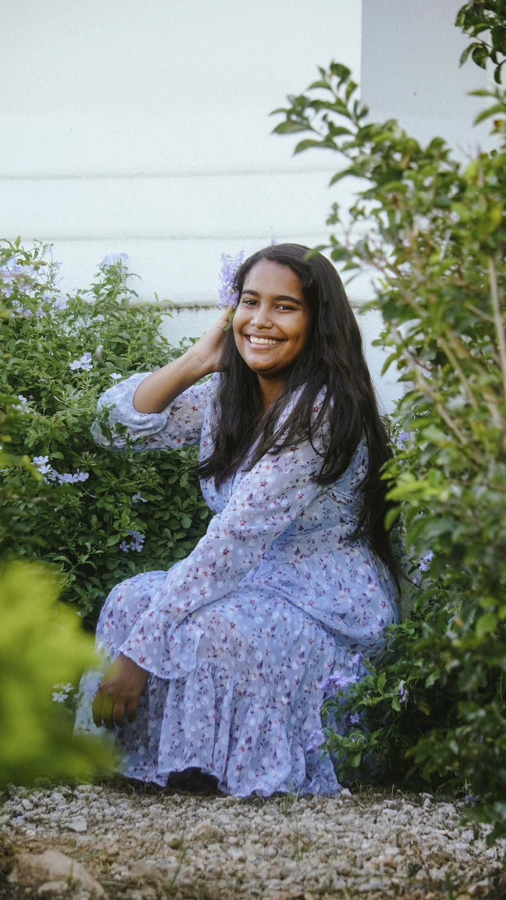 a woman in a blue dress sitting in a garden