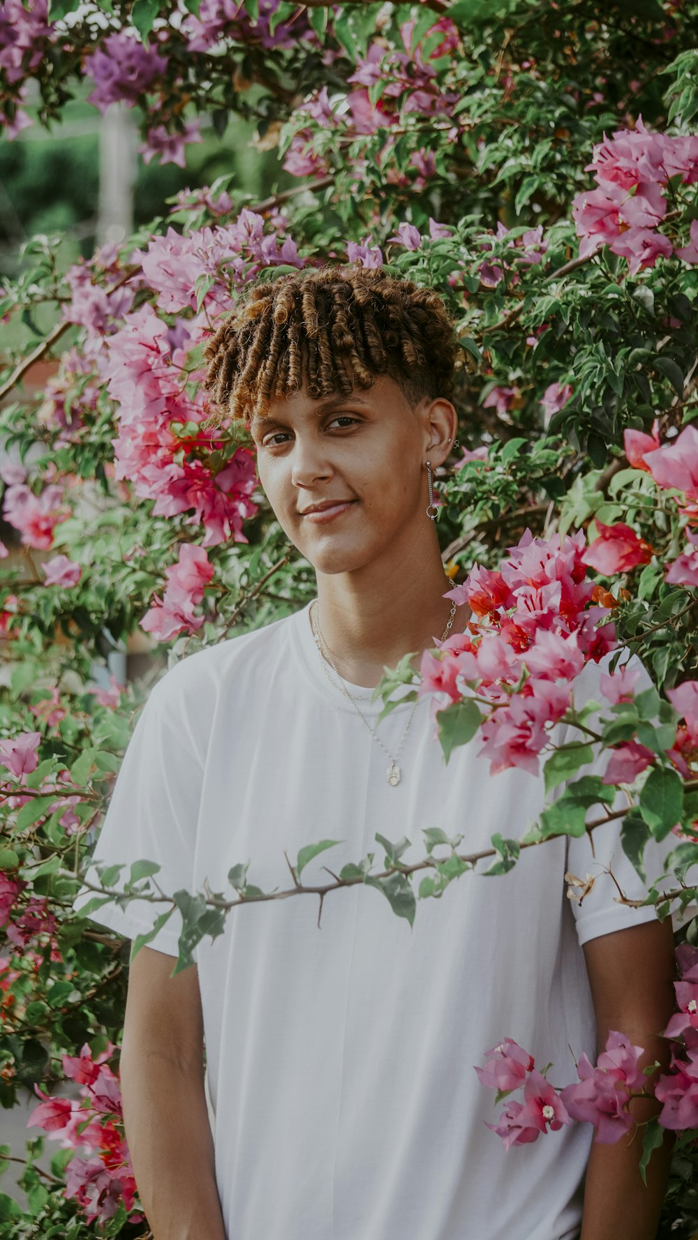 a person standing in front of a bush of flowers