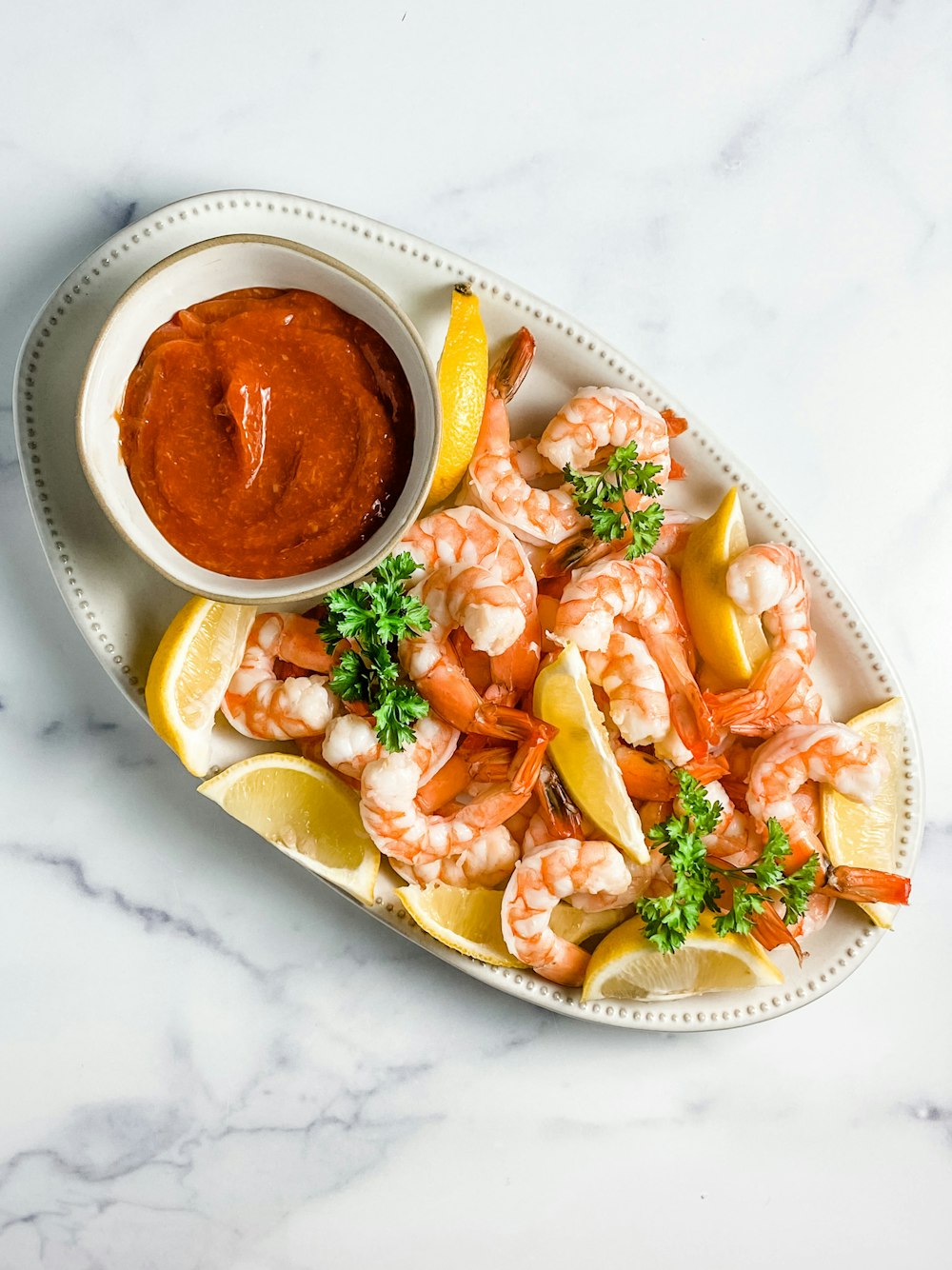a plate of shrimp and lemons with a dipping sauce