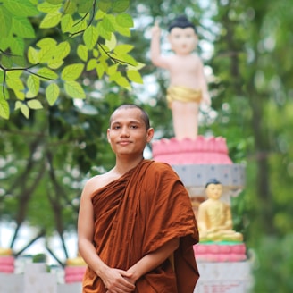 a young monk standing in front of a statue