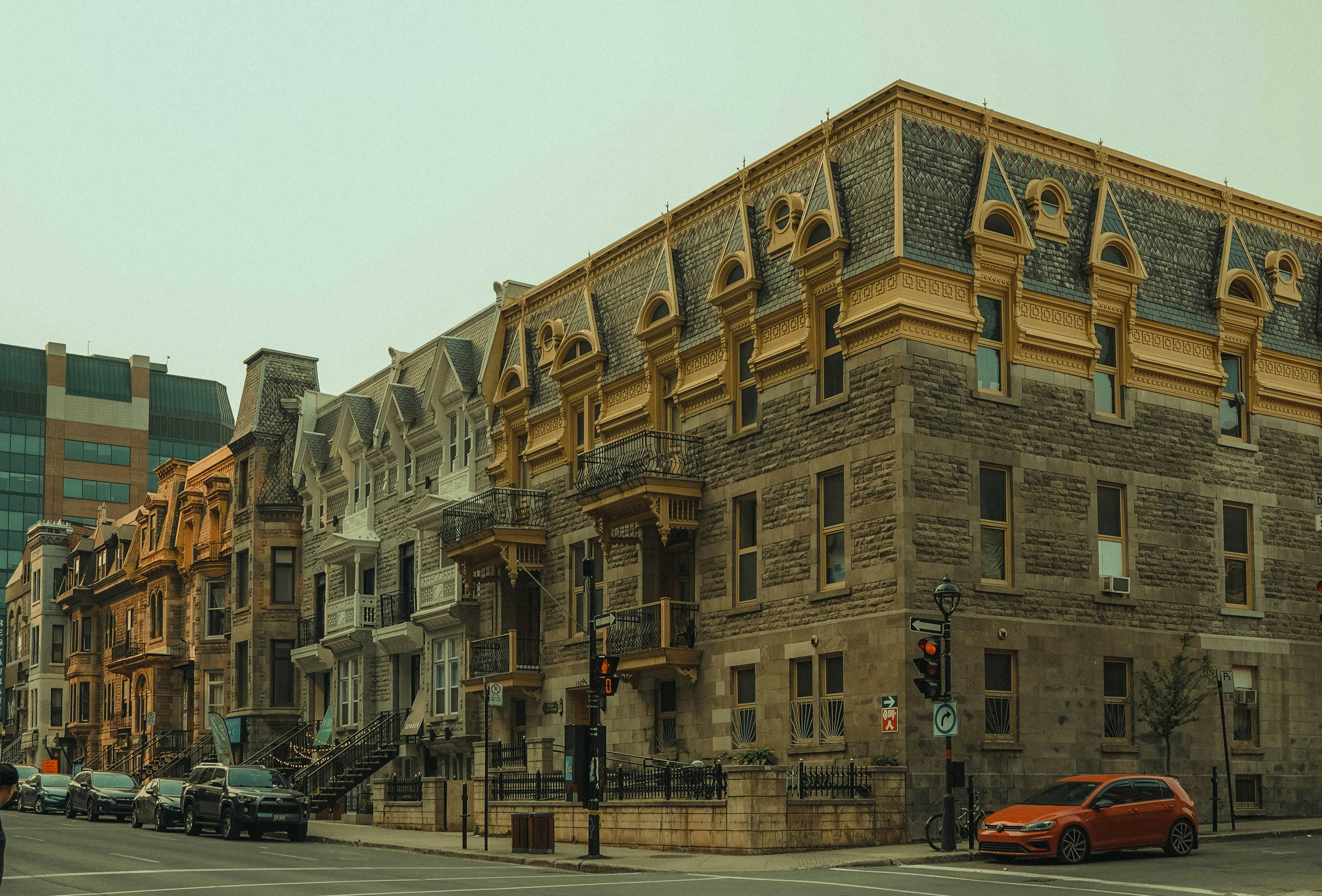 a red car driving down a street next to tall buildings, 