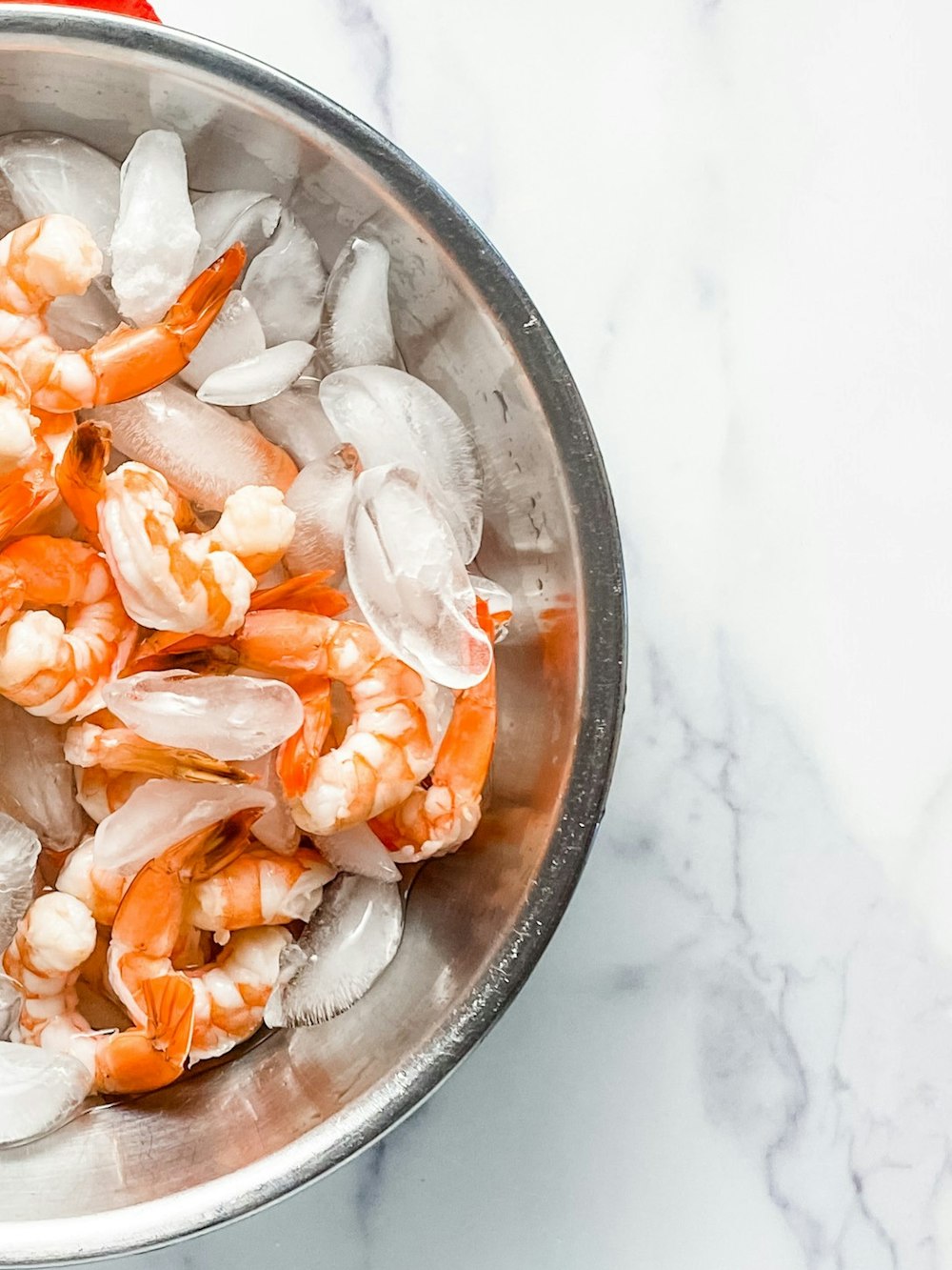 a metal bowl filled with shrimp on top of a table