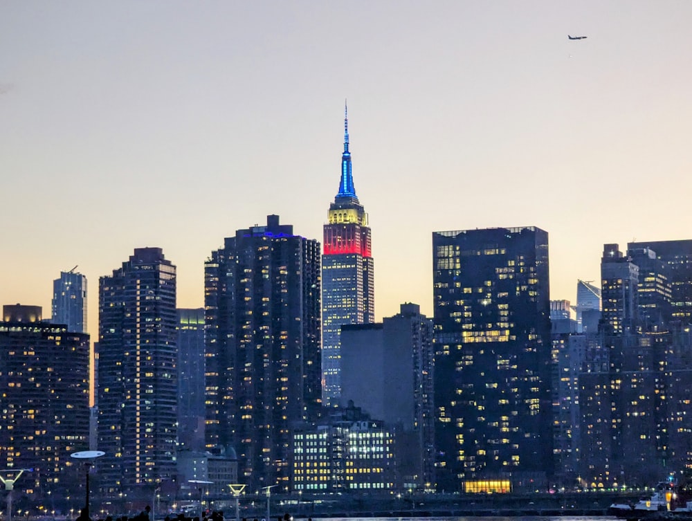 a city skyline with a plane flying over it