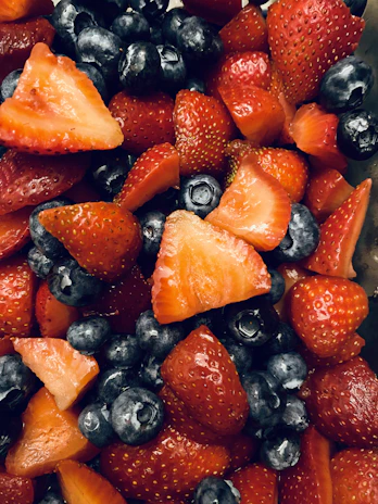 Close-up of fresh berries being gently mixed with natural protein powder in a wooden bowl.