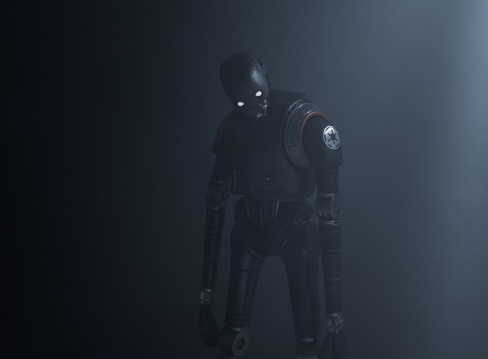 a robot standing in a dark room with a light coming from behind it