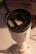 A cylindrical security camera with the brand name visible on its side, positioned on a white surface. The camera lens and sensor are prominent, and it is attached to a mounting bracket.