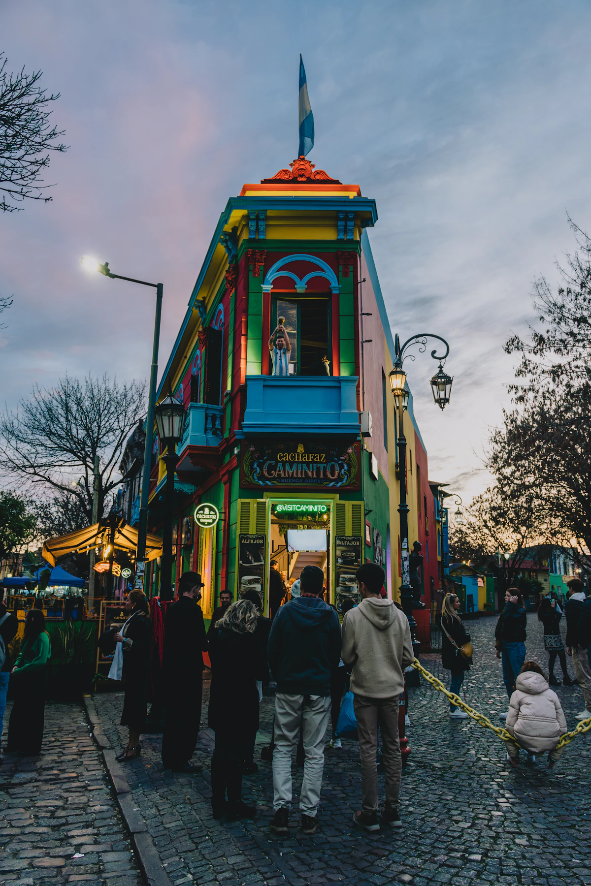 Visitors outside a brightly painted building in Caminito, La Boca, at dusk