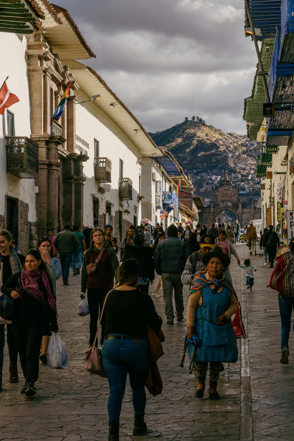 a crowd of people walking down a street next to tall buildings