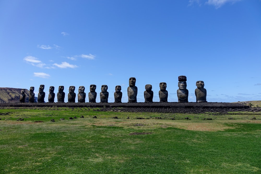 a large group of statues sitting on top of a lush green field