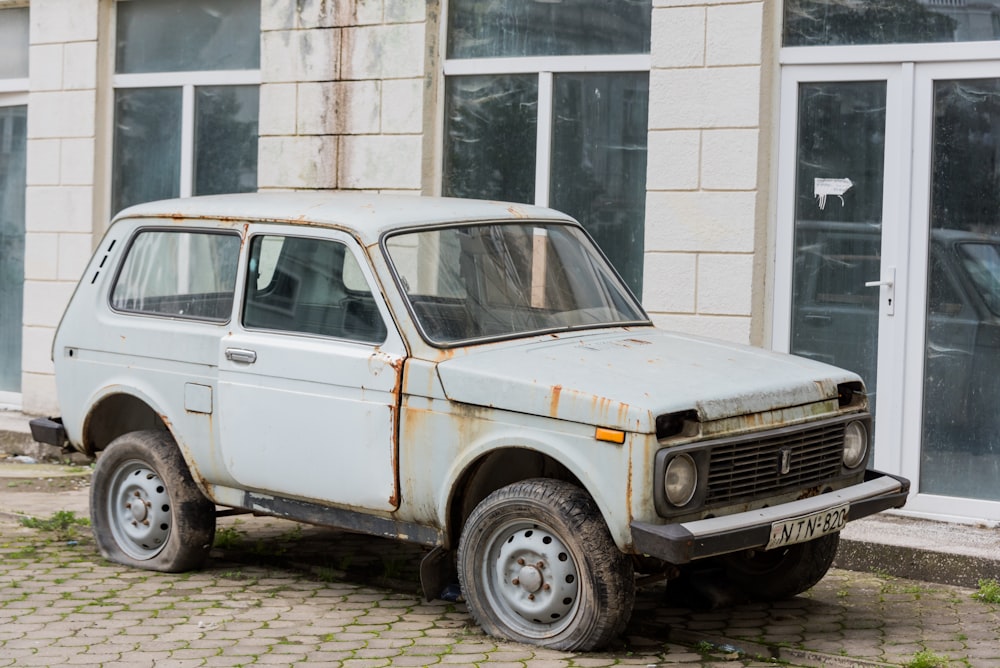 a rusted out car parked in front of a building