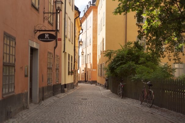 A charming cobblestone street lined with pastel-colored buildings bathed in soft seafoam green light