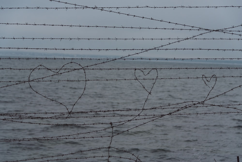 um par de corações desenhados em uma cerca de arame farpado