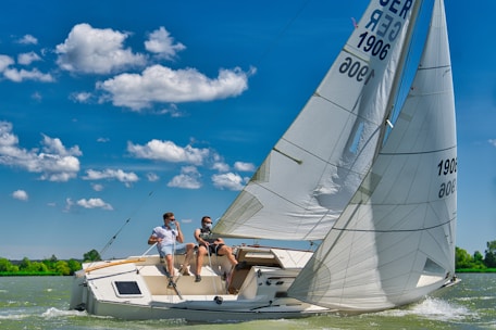 A happy couple preparing their sailboat for a day trip under clear blue skies.