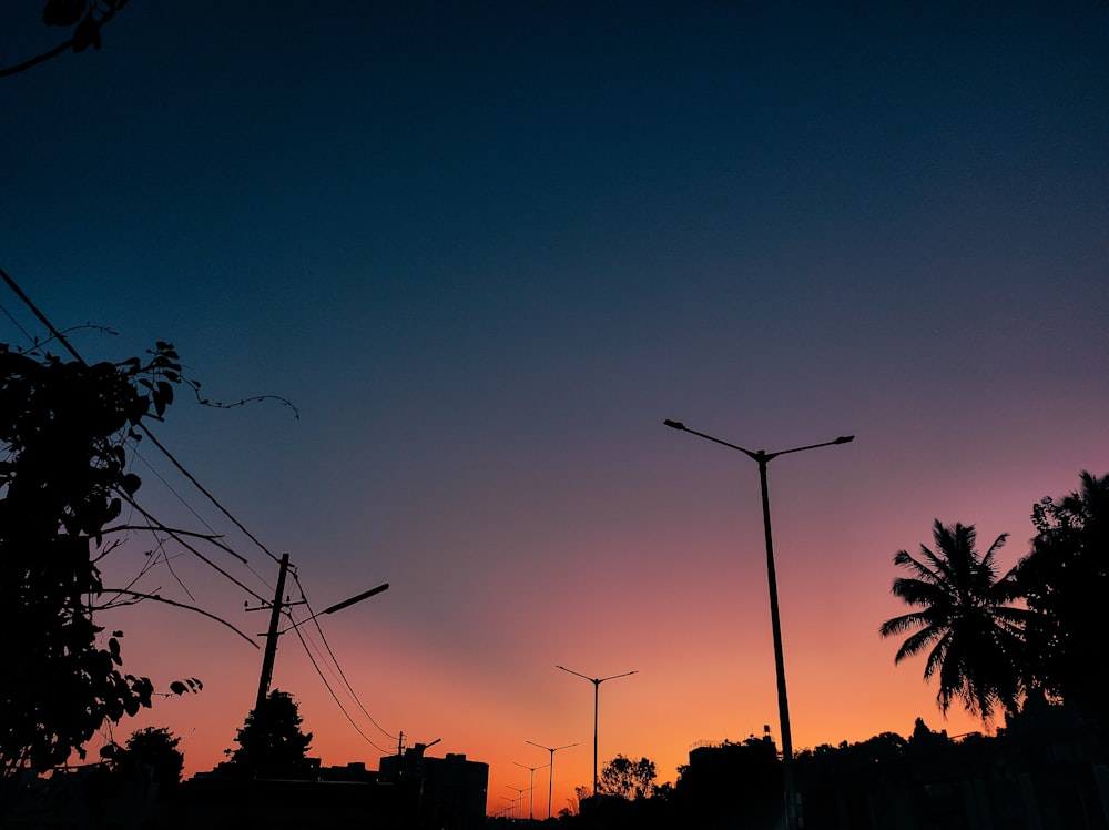 the sun is setting over a city with palm trees