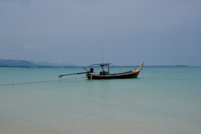 A traditional wooden boat floating on calm blue waters near a remote island.