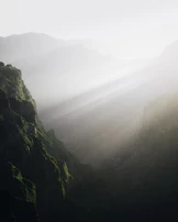 A serene morning view over the valley with soft mist weaving through rugged sandstone cliffs.