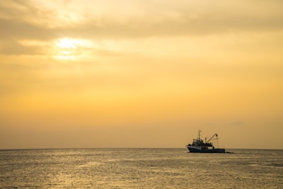 A fishing vessel at sea during sunrise.