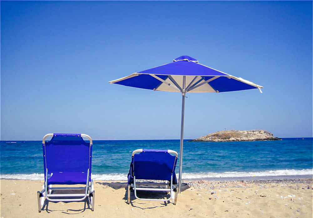 two lawn chairs and an umbrella on a beach