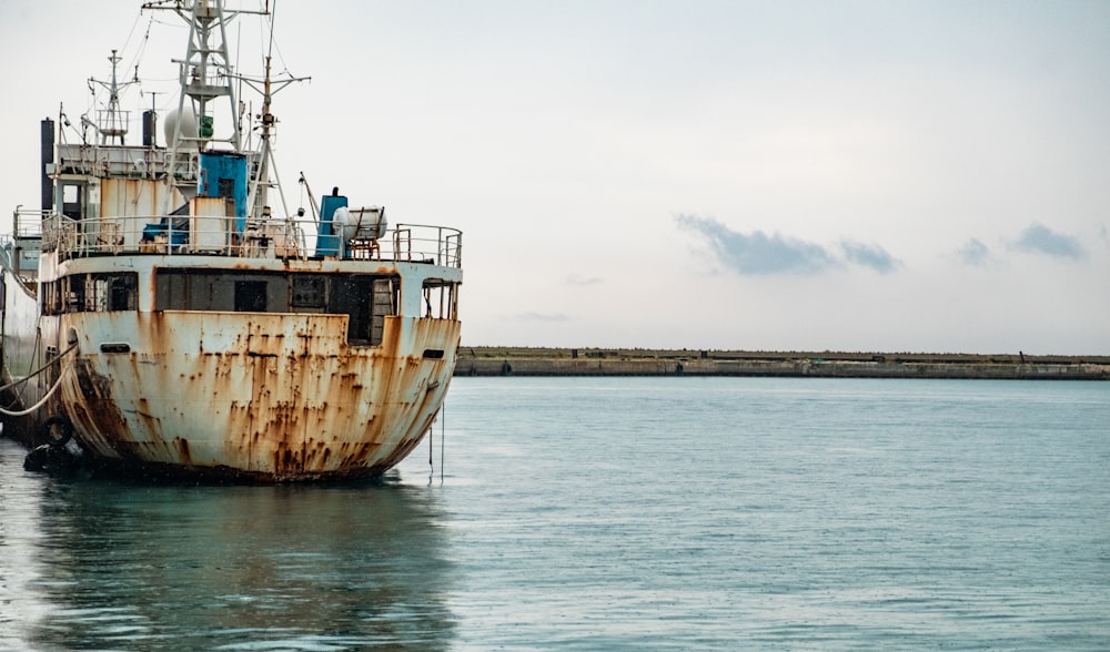 a rusted ship sitting in the middle of a body of water