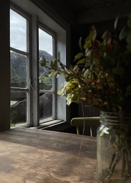 A rustic pottery piece resting on a wooden table with snowy mountains visible through a nearby window
