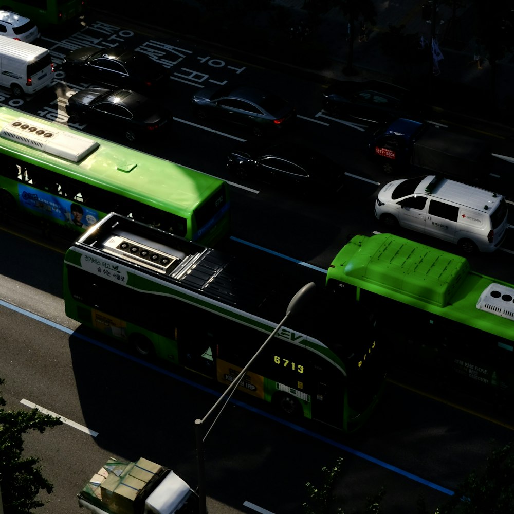 a green bus driving down a street next to a white car