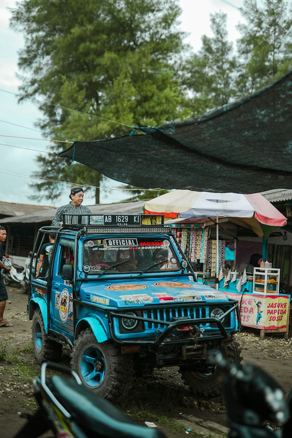 a man standing on top of a blue jeep