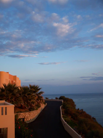 Cozy beachfront villa with palm trees and turquoise sea in the background during sunset.