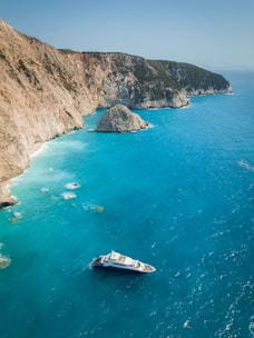 A captain guiding a yacht through sparkling coastal waters.