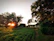 Sunset view over green fields and forest surrounding a charming countryside vacation home.